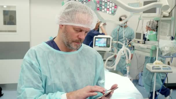 Cirurgião usa tablet na sala de cirurgia
 - Filmagem, Vídeo