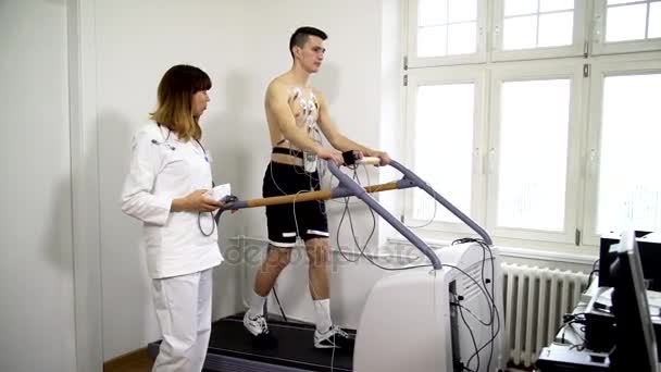 Female doctor monitors the progress of the a young man ECG - Video, Çekim