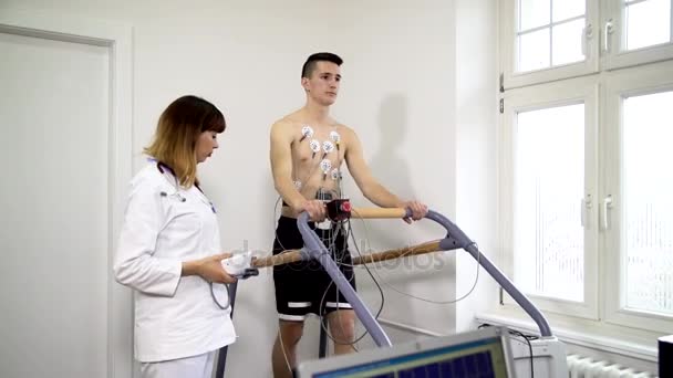 Female doctor monitors the progress of the a young man ECG - Metraje, vídeo