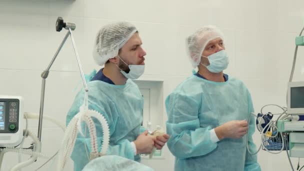 Cirurgião aponta a mão no monitor
 - Filmagem, Vídeo