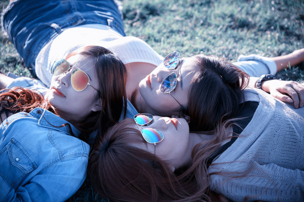 Három Asia boldog lány feküdt a zöld fű, napszemüveg - Fotó, kép