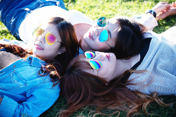 Tři dívky Asie leží na zelené trávě v sluneční brýle - Fotografie, Obrázek