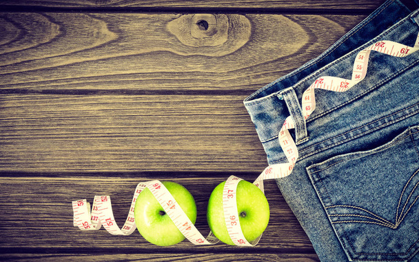 Koncepcja utraty wagi, niebieskie dżinsy, zielone jabłka i taśma pomiarowa - Zdjęcie, obraz