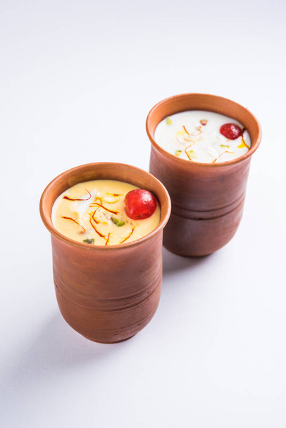 Аутентичный индийский холодный напиток из творога, молока и малая называется Lassi в шафран / кесарь вкус, также называемый kesariya или кешария или кесарь Ласси, служил в традиционных индийских терракотовых стаканах
 - Фото, изображение