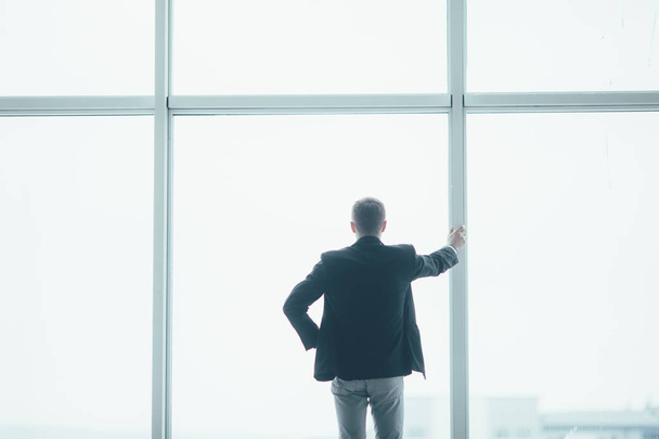Elegante uomo d'affari sullo sfondo di una grande finestra in ufficio
 - Foto, immagini
