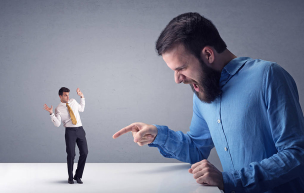 Young businessman fighting with miniature businessman - Фото, зображення