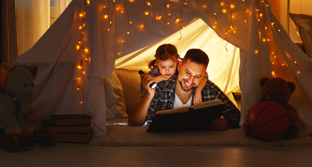 счастливый семейный отец с книгой для чтения в палатке на хоме
 - Фото, изображение
