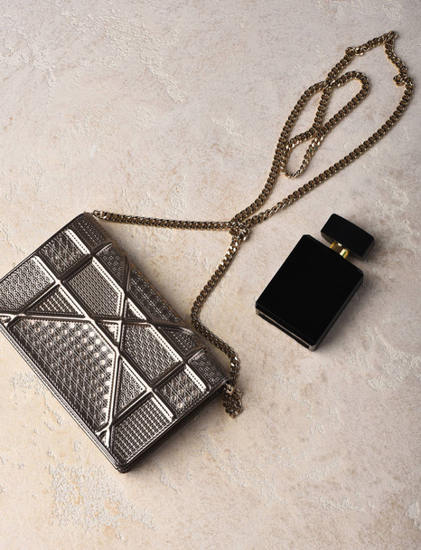 small womans metallized silver bag with metallic chain near perfume - Фото, изображение