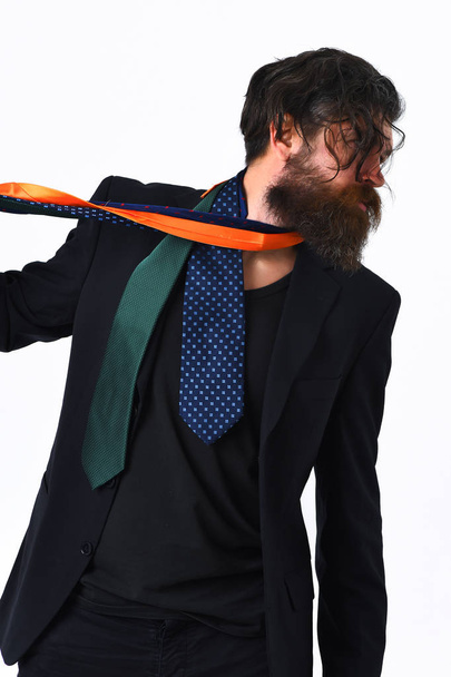 Brutal caucasian hipster in black suit holding ties around neck - 写真・画像