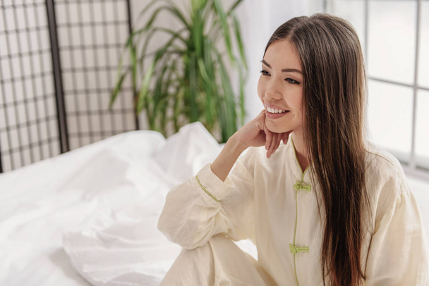 Pensive asian female dreaming on bed - Fotografie, Obrázek