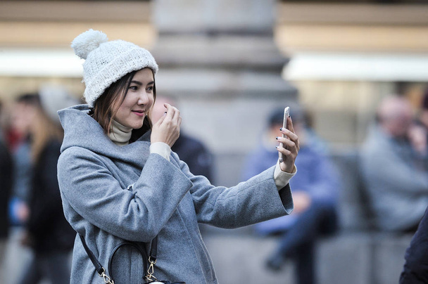 ITALY, FLORENCE - DEC 24 2016: Asian woman take selfie photo near the La republica. Over 1 Million selfies Are taken each day.Instagram has over 53 million photos tagged with the hash tag #selfie. - Foto, imagen