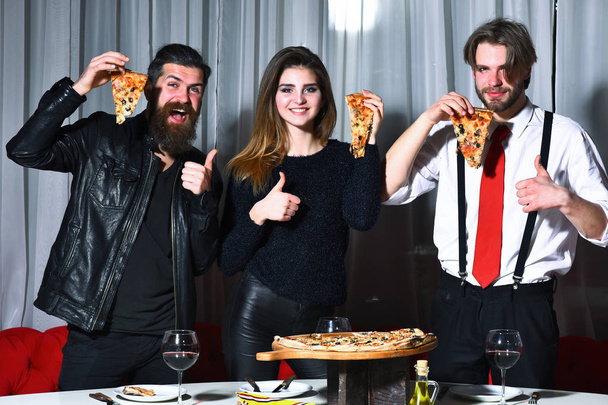 Happy friends eating tasty pizza slices with thumbs up gestures - Φωτογραφία, εικόνα