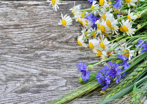 Een boeket van madeliefjes en korenbloemen op houten tafel. Ansichtkaart van wilde bloemen - Foto, afbeelding