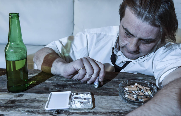 hombre alcohólico y drogadicto desperdiciado con corbata suelta inhalando cocaína y bebiendo botellas de cerveza en casa
  - Foto, imagen