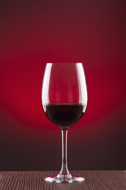 Glass of wine over red background - Фото, изображение
