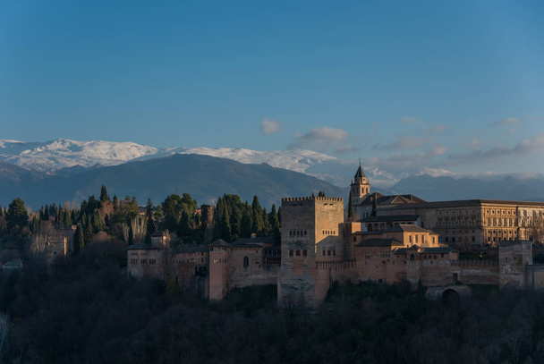 Widok na Pałac Alhambra w Granadzie z gór Sierra Nevada w śniegu w tle. Granada, Hiszpania. - Zdjęcie, obraz