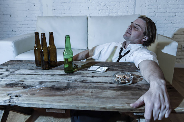 hombre alcohólico y drogadicto desperdiciado con corbata suelta inhalando cocaína y bebiendo botellas de cerveza en casa
  - Foto, imagen