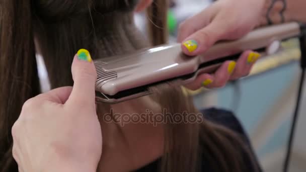 Používání žehličky na dlouhé vlasy klienta v kadeřnictví kadeřník - Záběry, video