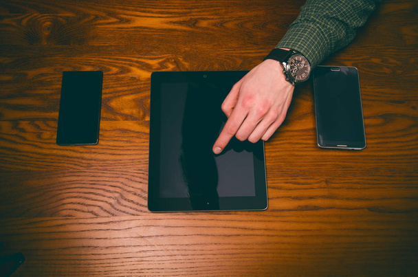 Hombre toque la mano en una pantalla de teléfono móvil en una mesa de madera. Situación empresarial
 - Foto, Imagen