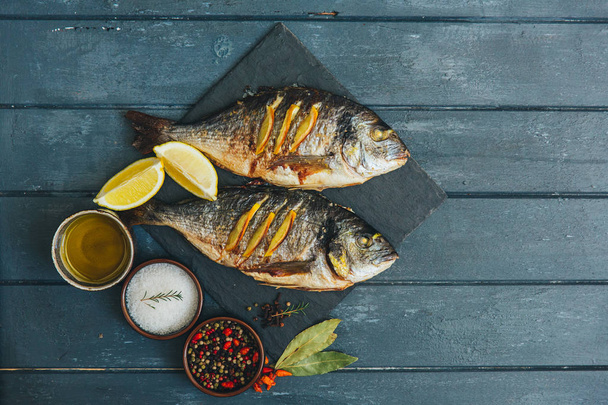 Roasted gilthead fish with spices over wooden background  - Valokuva, kuva