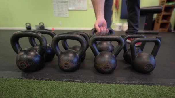Man picks up kettle bells and starts working out - Footage, Video