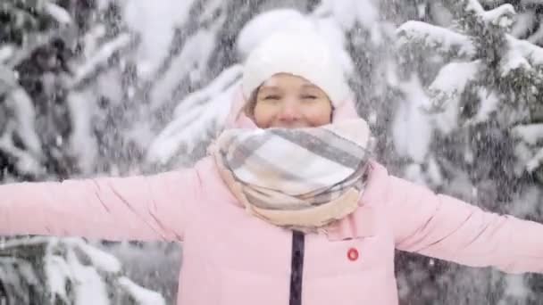 Молода щаслива жінка насолоджується зимовим днем на відкритому повітрі в лісі. Жінка кидає пухнастий сніг вгору повільний рух
 - Кадри, відео