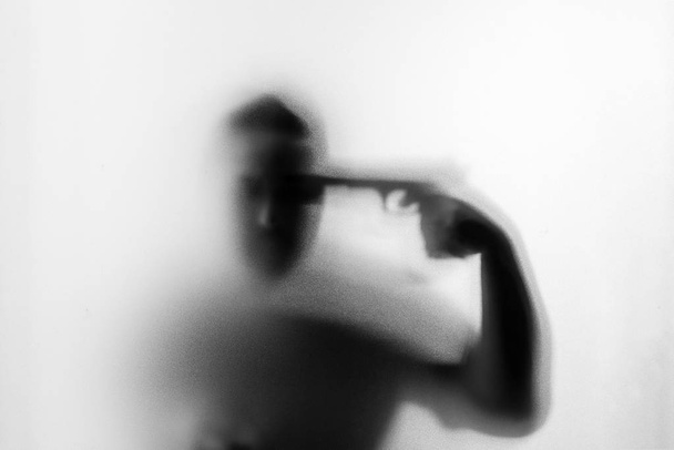 Σκιά του τρόμου άνθρωπος δολοφόνος με ένα πυροβόλο όπλο στο χέρι του. Επικίνδυνος άνθρωπος - Φωτογραφία, εικόνα