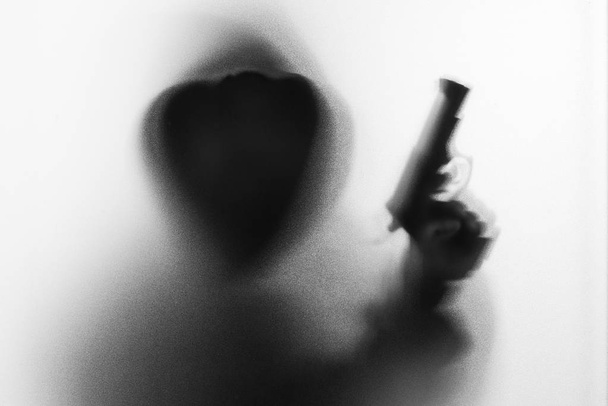 Schattenwurf des Horror-Mannes in Jacke mit Kapuzenpulli in der Hand.da - Foto, Bild