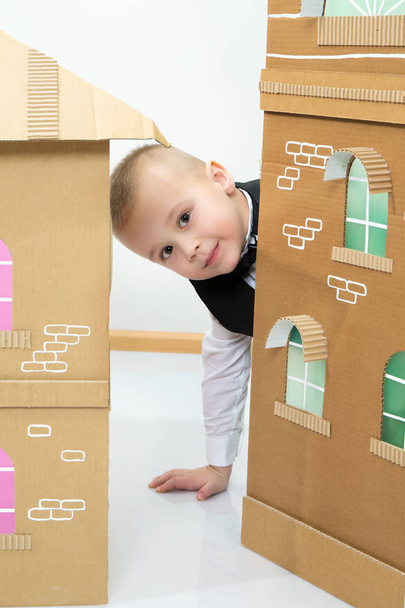 Boy peeks out from behind the cardboard house. - Foto, Bild