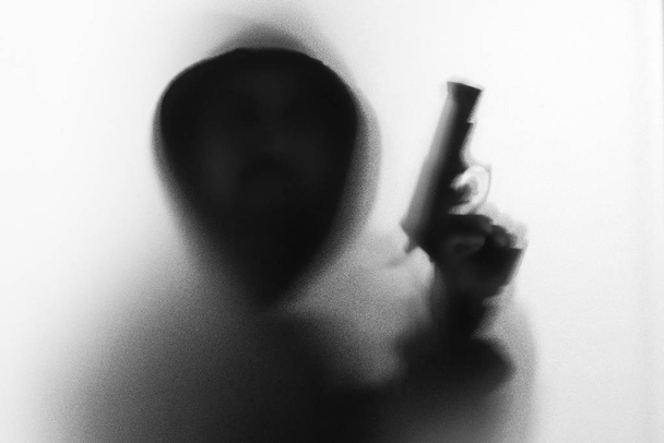Shadow blur of horror man in jacket with hood gun in his hand.Da - Photo, Image