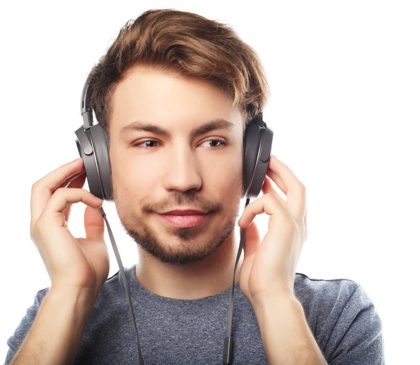 Handsome young man wearing headphones and smiling while standing - Valokuva, kuva