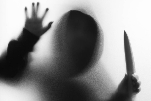 Árnyék, életlenítés horror férfi kabát kapucnival késsel a kezében. - Fotó, kép
