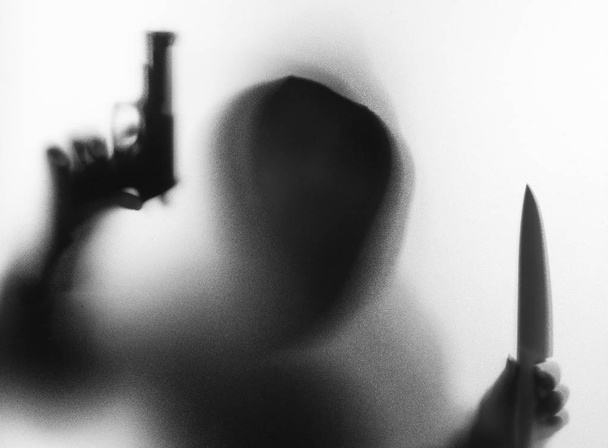 Gölge görüntü korku adamın ceketi giyen hood bıçak ve silah h ile - Fotoğraf, Görsel