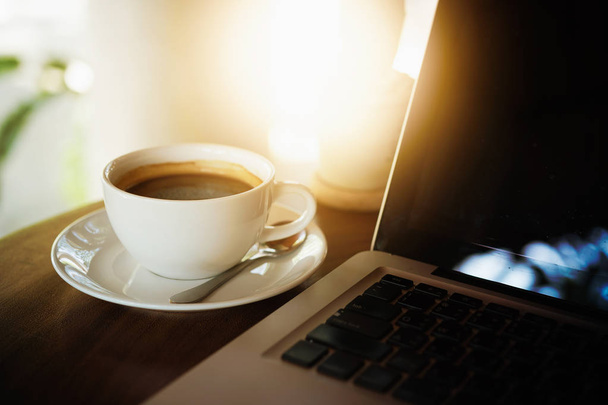 Чашка кофе и ноутбук на деревянном столе - Фото, изображение