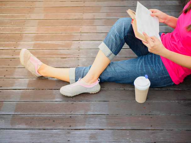 Young pretty woman sitting at outdoor drinking coffee and reading a book enjoys of rest - Fotoğraf, Görsel