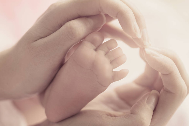 Mooie moeder handen houden Baby voet en Making hart.  - Foto, afbeelding
