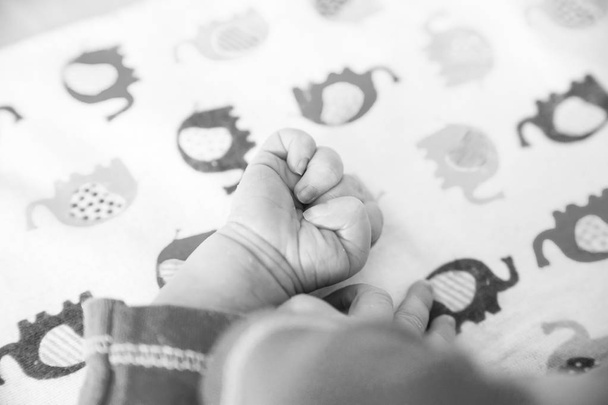Die Hand eines Neugeborenen wird in einer Faust eingeklemmt. - Foto, Bild