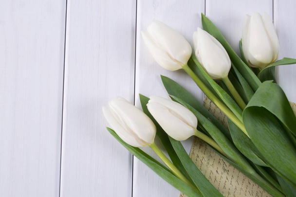 Primer plano de tulipanes blancos y papel o carta en blanco
  - Foto, Imagen