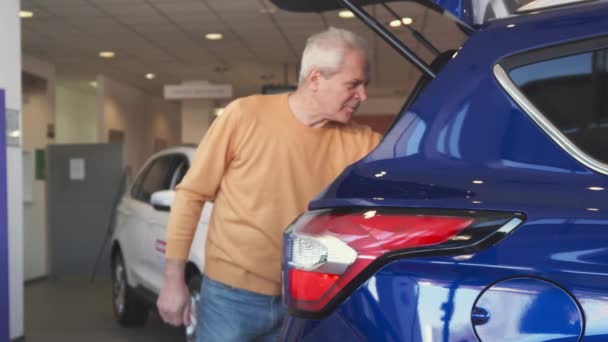 Vanhempi mies avaa auton takakontin jälleenmyyntisopimuksessa
 - Materiaali, video