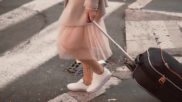 Close-up view of traveling woman across street at crosswalk. Girl with suitcase moving to the new flat. Slow motion. - Filmati, video