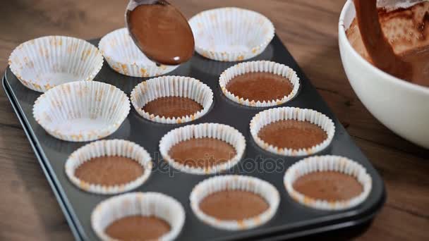 A tésztát helyezett papír cups. Kézzel töltött sütemény tészta muffin tálca - Felvétel, videó