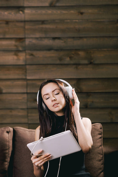 pretty brunette girl on the sofa listening music with closed eyes - Photo, image