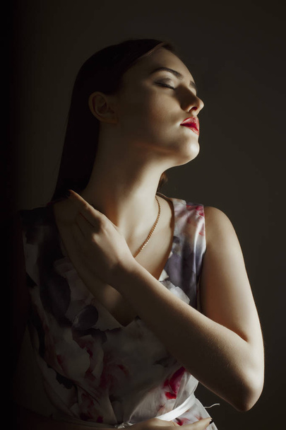 Αισθησιακό μελαχρινή γυναίκα με φόρεμα που ποζάρουν στο σκοτεινό δωμάτιο  - Φωτογραφία, εικόνα
