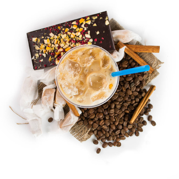 Ice coffee in takeaway cup, chocolate bar and coffee beans on wooden background - Fotó, kép