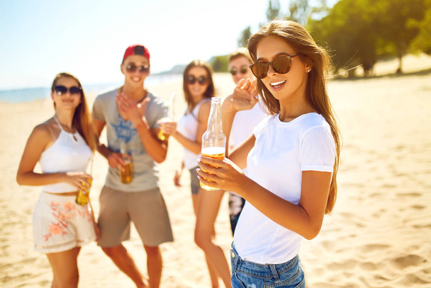 Group of friends hanging out with beer at the beach.  Excellent sunny weather. Beautiful figures.Summer concept - Foto, immagini