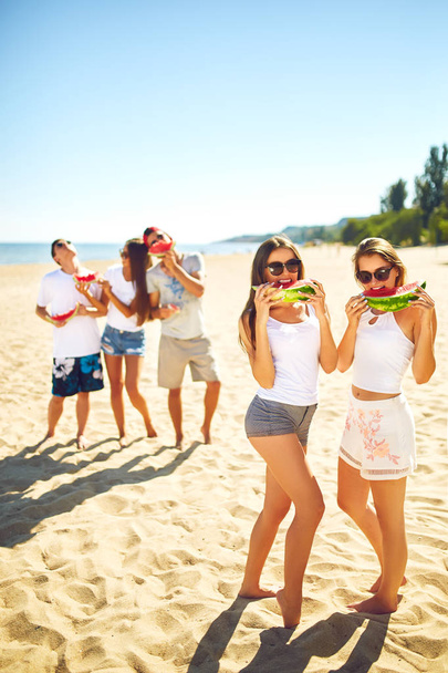 Groupe d'amis s'amuser à manger de la pastèque. sur la plage. Très beau temps ensoleillé. . Super humeur. Concept d'été
 - Photo, image
