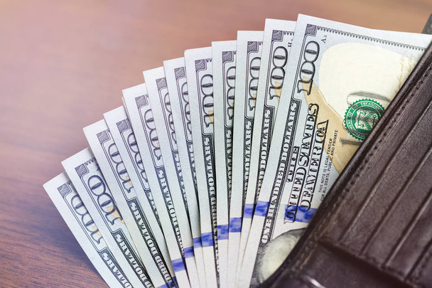 Гаманець із сотнею доларових банкнот на дерев'яному фоні, концепція грошей та фінансів
 - Фото, зображення