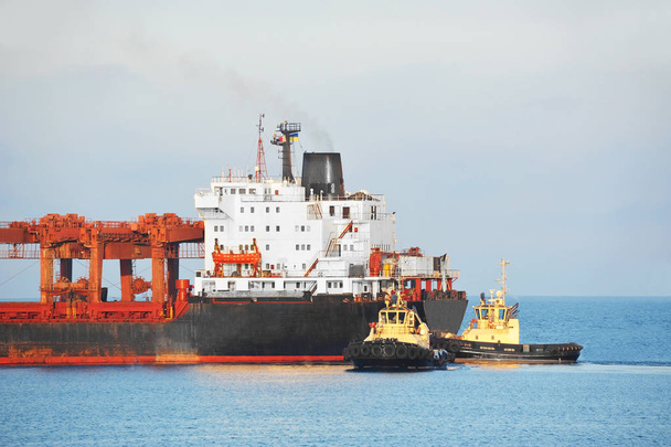 Буксир, помогающий грузовому судну
 - Фото, изображение