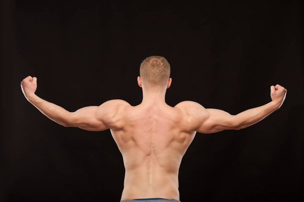 Athletic handsome sportsman fitness-model showing his muscular back. isolated on black background with copyspace - Valokuva, kuva