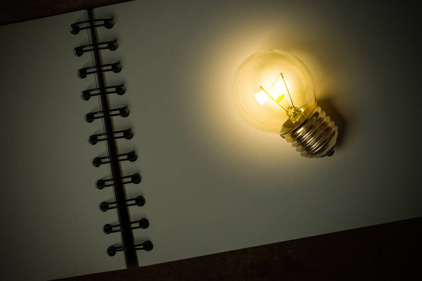 A Light Bulb Placed on an Opened Sketchbook - Photo, Image